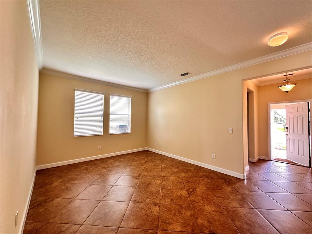 An empty room with tan walls, tile flooring, and a view of an open doorway — 7409 FAIRGROVE AVENUE, WINDERMERE, FL