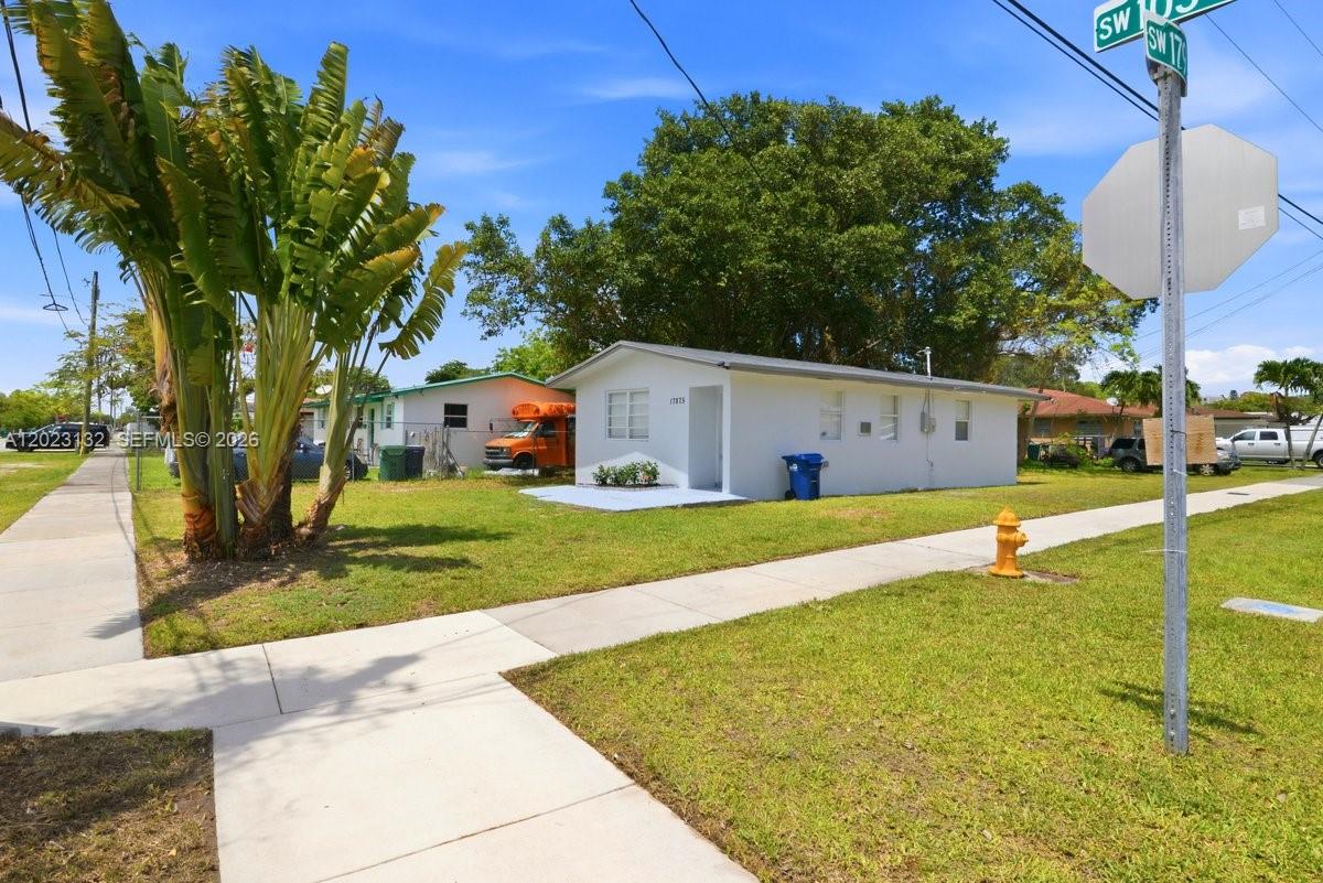 A small, white, single-story house sits on a grassy lot next to a chain-link fence — 17875 SW 103rd Ave, Miami FL 33157, MIAMI, FL