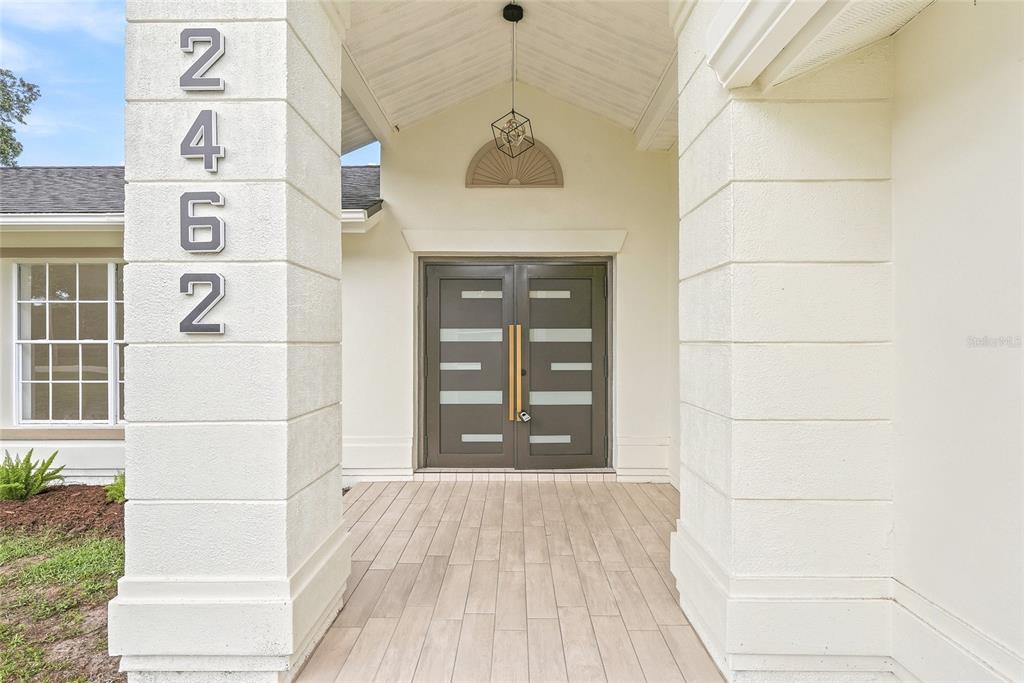A covered front porch features a double door entrance and large house numbers on a pillar — 2462 STEPHANIE DRIVE, SPRING HILL, FL