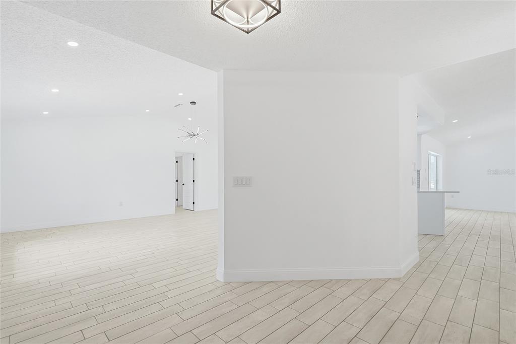 A bright, open-concept living and dining area features light wood-look tile flooring and modern furniture — 2462 STEPHANIE DRIVE, SPRING HILL, FL