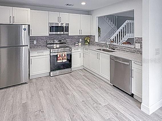 A kitchen with white cabinets, stainless steel appliances, and light wood-look flooring — 4402 RING NECK ROAD UNIT 19B, ORLANDO, FL