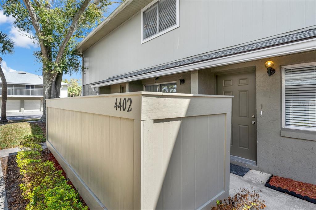 The exterior of a two-story townhouse features a privacy fence and a brown front door — 4402 RING NECK ROAD UNIT 19B, ORLANDO, FL