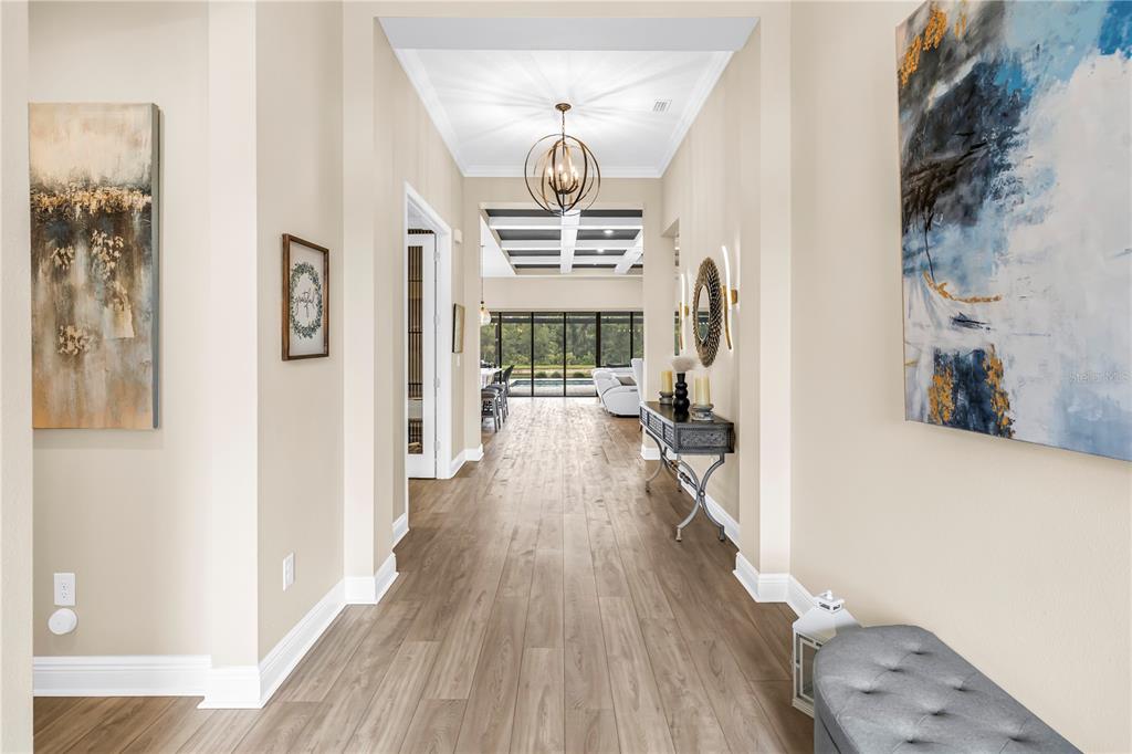 An entryway features a gray tufted bench, double glass-paneled doors, and light wood-look flooring — 9279 WARM SPRINGS CIRCLE, PARRISH, FL