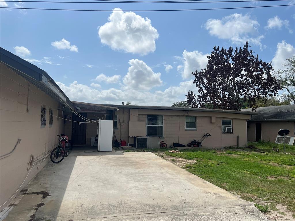 The exterior of a single-story concrete block house features a concrete driveway and yard — 617 E MYERS BOULEVARD, MASCOTTE, FL