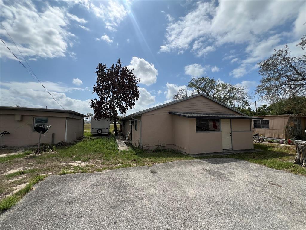 A tan, single-story house with a gravel driveway and a small tree in the yard — 617 E MYERS BOULEVARD, MASCOTTE, FL