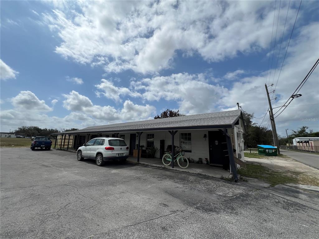 A single-story building with a covered porch, a parked white SUV, and a bicycle — 617 E MYERS BOULEVARD, MASCOTTE, FL