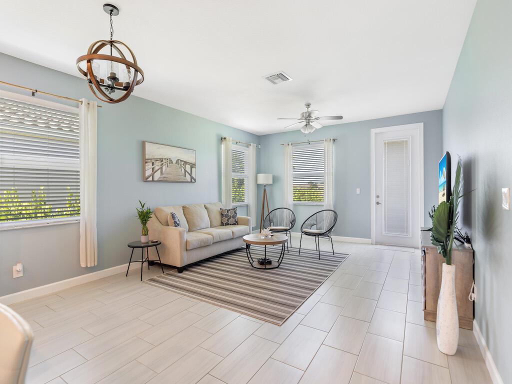 A living room features light blue walls, tile flooring, a sofa, and a globe chandelier — 1786 Berkshire Circle SW, Vero Beach FL 32968, VERO BEACH, FL