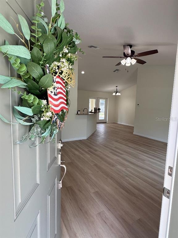 A view from a doorway into an open-concept living area with light wood-look flooring — 20115 SW 83RD PLACE, DUNNELLON, FL