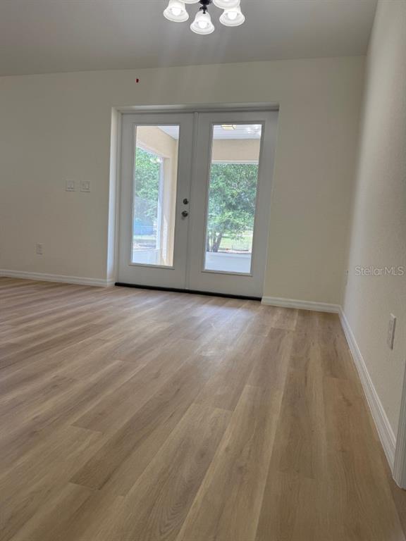 A room with light wood-look flooring and a set of double glass doors — 20115 SW 83RD PLACE, DUNNELLON, FL