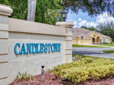 A beige monument sign with blue lettering stands in front of a suburban residential street — 13729 SE 89TH AVENUE, SUMMERFIELD, FL