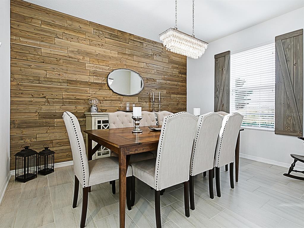 A dining room features a wood-plank accent wall, a crystal chandelier, and a wooden table — 417 BLUE CYPRESS DRIVE, GROVELAND, FL