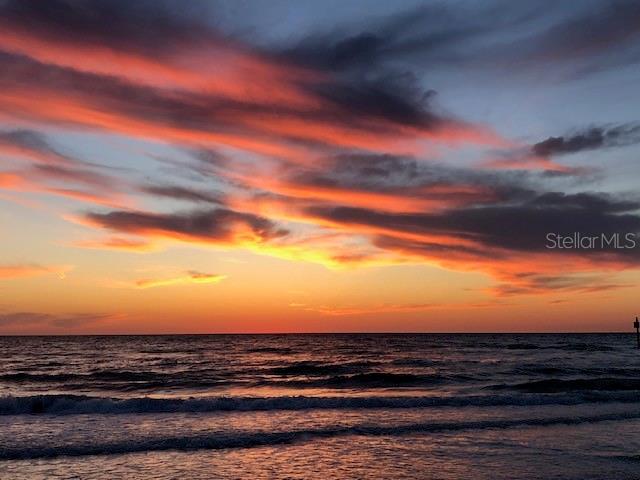 A vibrant sunset over the ocean with dark clouds and waves hitting the shore — 833 LANTANA AVENUE, CLEARWATER BEACH, FL