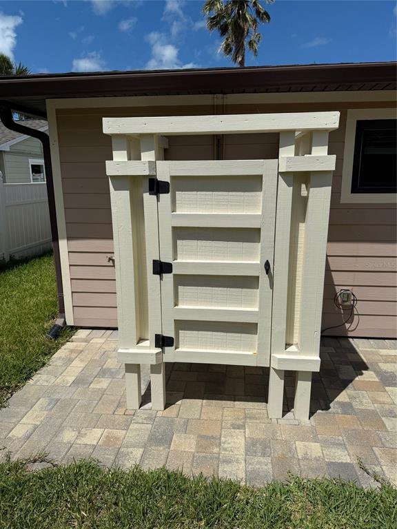 An outdoor wooden shower enclosure stands on a paved patio against the side of a house — 833 LANTANA AVENUE, CLEARWATER BEACH, FL