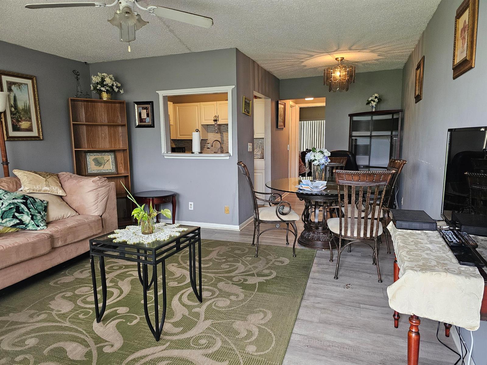 A living room and dining area with gray walls, wood-look flooring, and a ceiling fan — 102 Easthampton E, West Palm Beach FL 33417, WEST PALM BEACH, FL