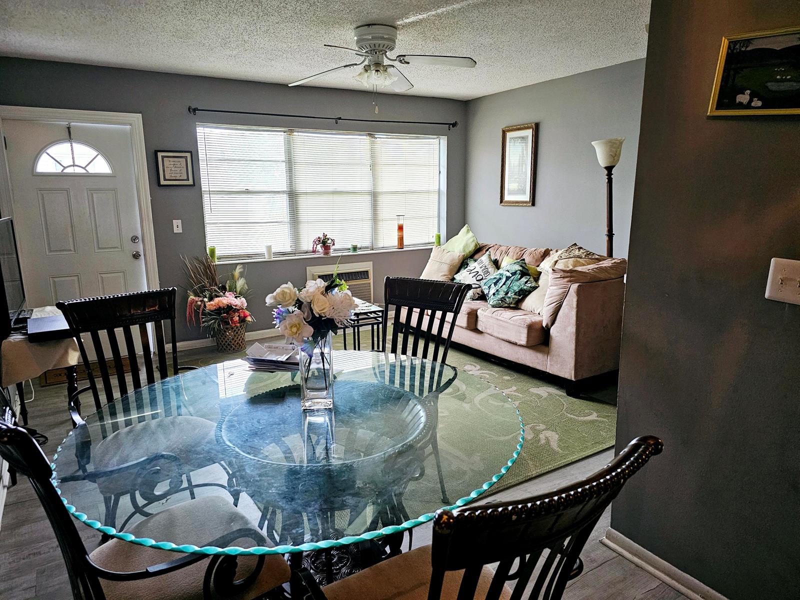 A dining area with a glass table and chairs opens into a living room space — 102 Easthampton E, West Palm Beach FL 33417, WEST PALM BEACH, FL
