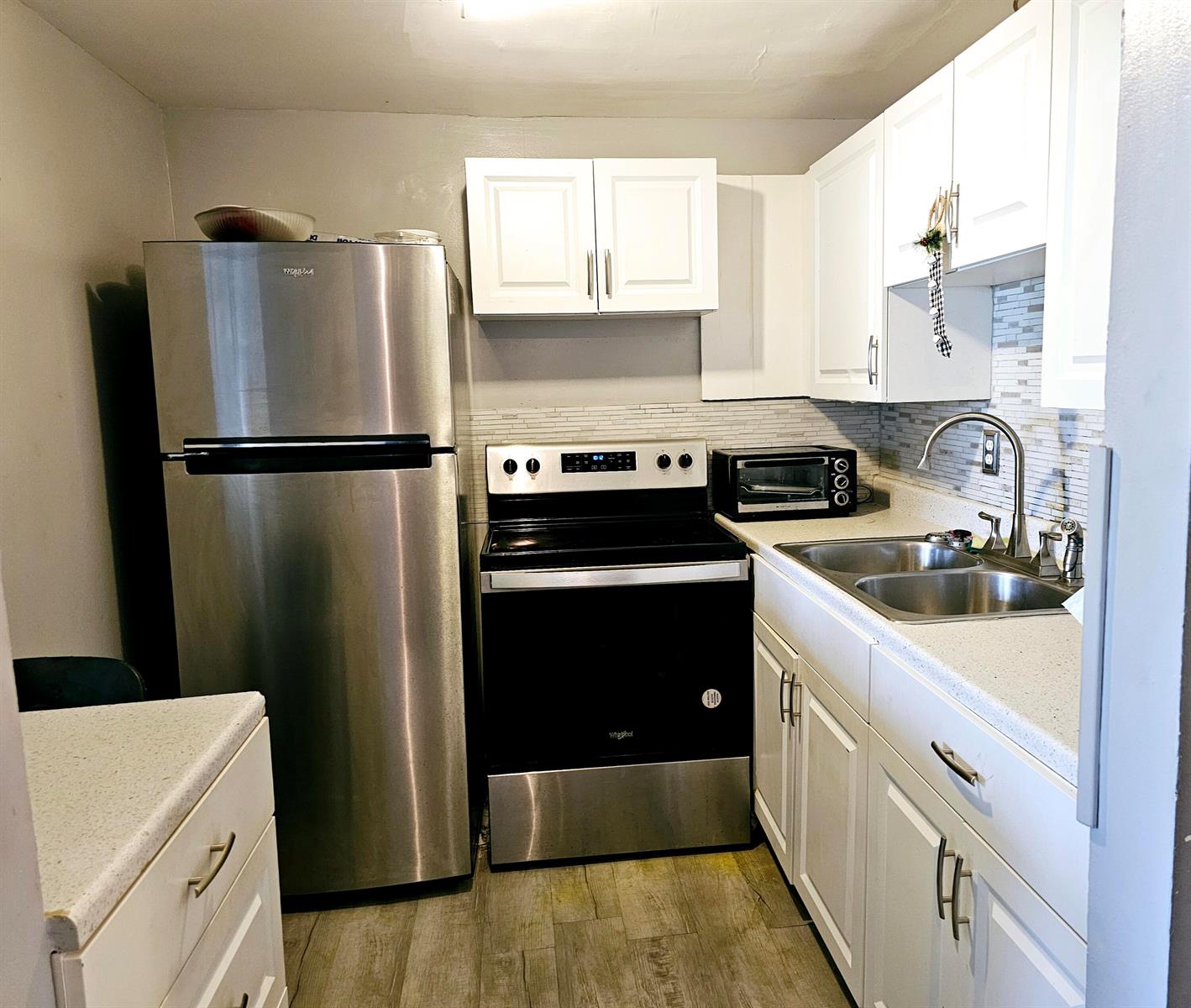 A small kitchen features stainless steel appliances, white cabinets, and a light-colored countertop — 102 Easthampton E, West Palm Beach FL 33417, WEST PALM BEACH, FL