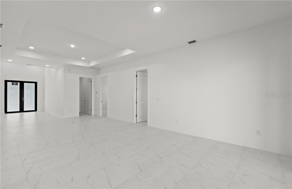 A bright, minimalist room features white walls, white tile flooring, and a recessed ceiling — 3927 NW 40TH TERRACE, CAPE CORAL, FL