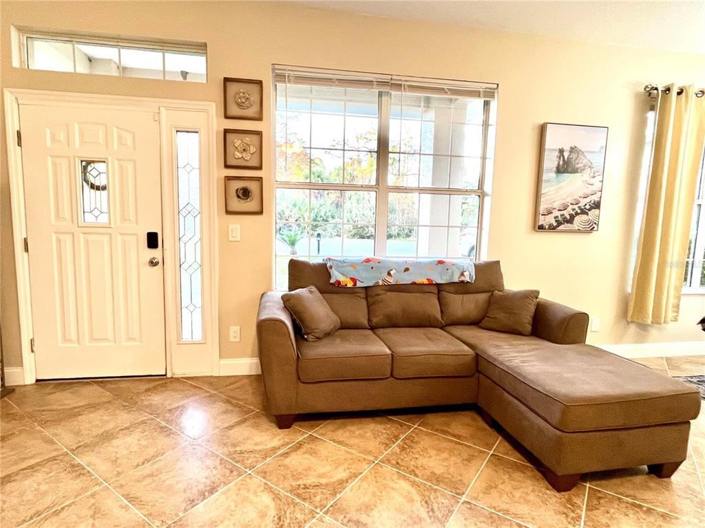 A living room features a brown sectional sofa, tiled floors, and a front entryway — 14 SQUASH BLOSSOM COURT, PALM COAST, FL