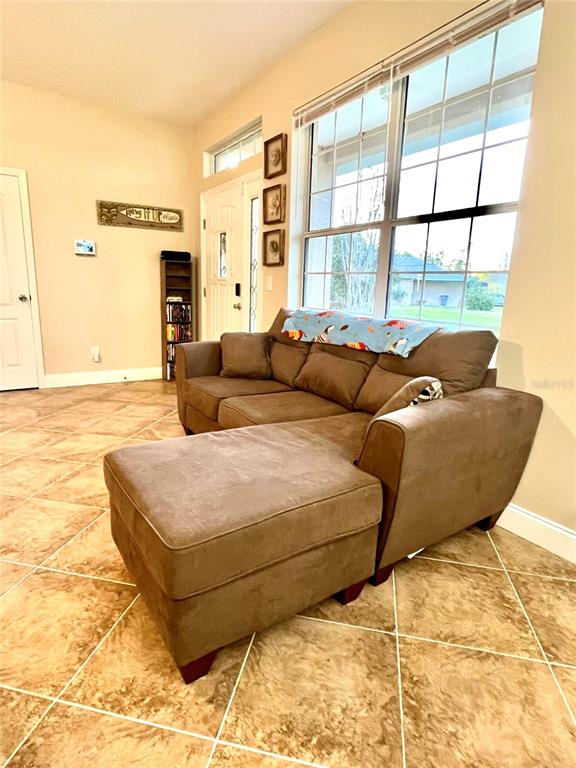 A brown sectional sofa sits on a tiled floor in a room with large windows — 14 SQUASH BLOSSOM COURT, PALM COAST, FL