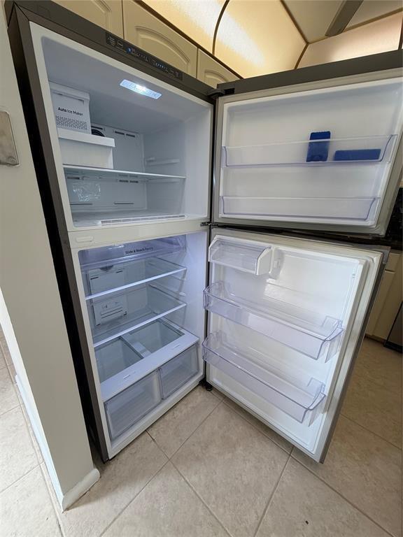 An open stainless steel top-freezer refrigerator stands in a kitchen with tiled flooring — 84 Mansfield B # 84, Boca Raton FL 33434, BOCA RATON, FL