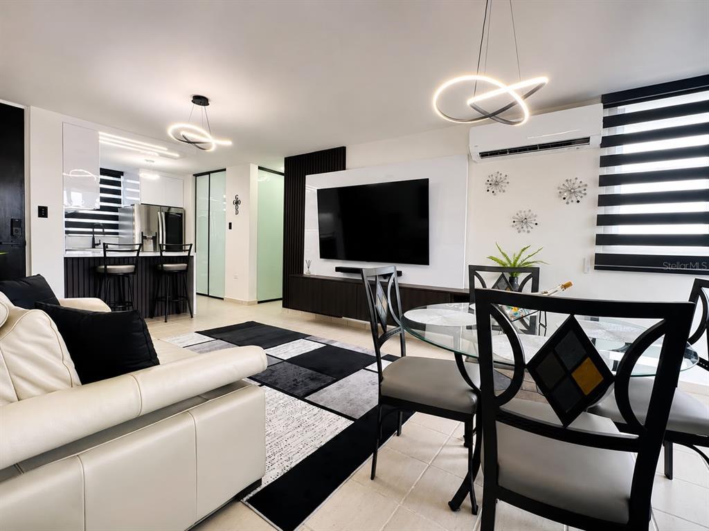 A modern living room features a wall-mounted television, wood slat paneling, and a geometric rug — COND. COSTA BRAVA EDIF. 9 UNIT #301, CEIBA, PR