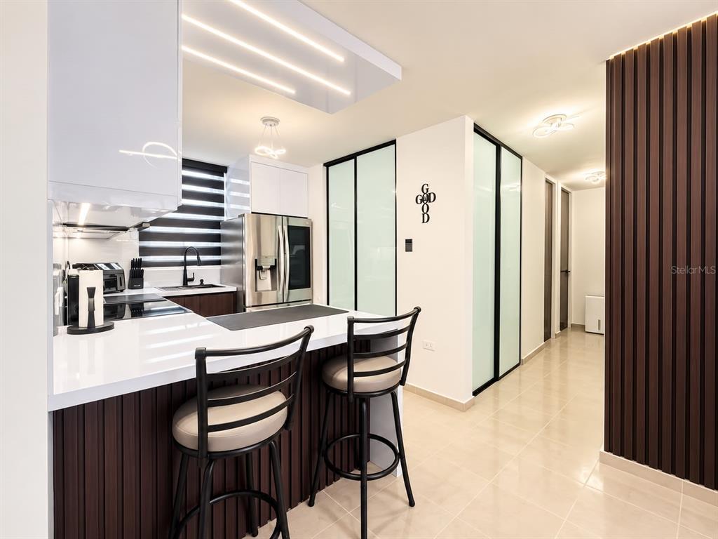 A modern living and dining area features a white sofa, glass table, and wall-mounted television — COND. COSTA BRAVA EDIF. 9 UNIT #301, CEIBA, PR