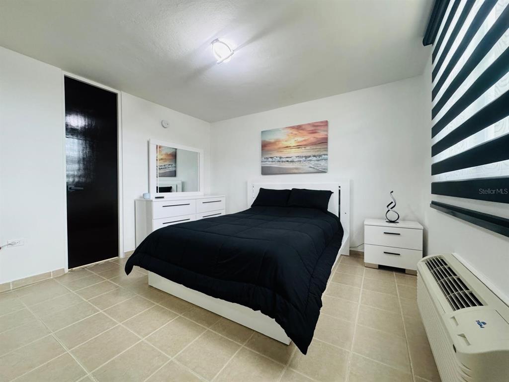 A modern kitchen features a white breakfast bar, dark wood paneling, and stainless steel appliances — COND. COSTA BRAVA EDIF. 9 UNIT #301, CEIBA, PR