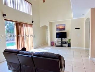 A living room with high ceilings, tile floors, a television, and sliding glass doors — 1906 SE 18th St, Homestead FL 33035, HOMESTEAD, FL