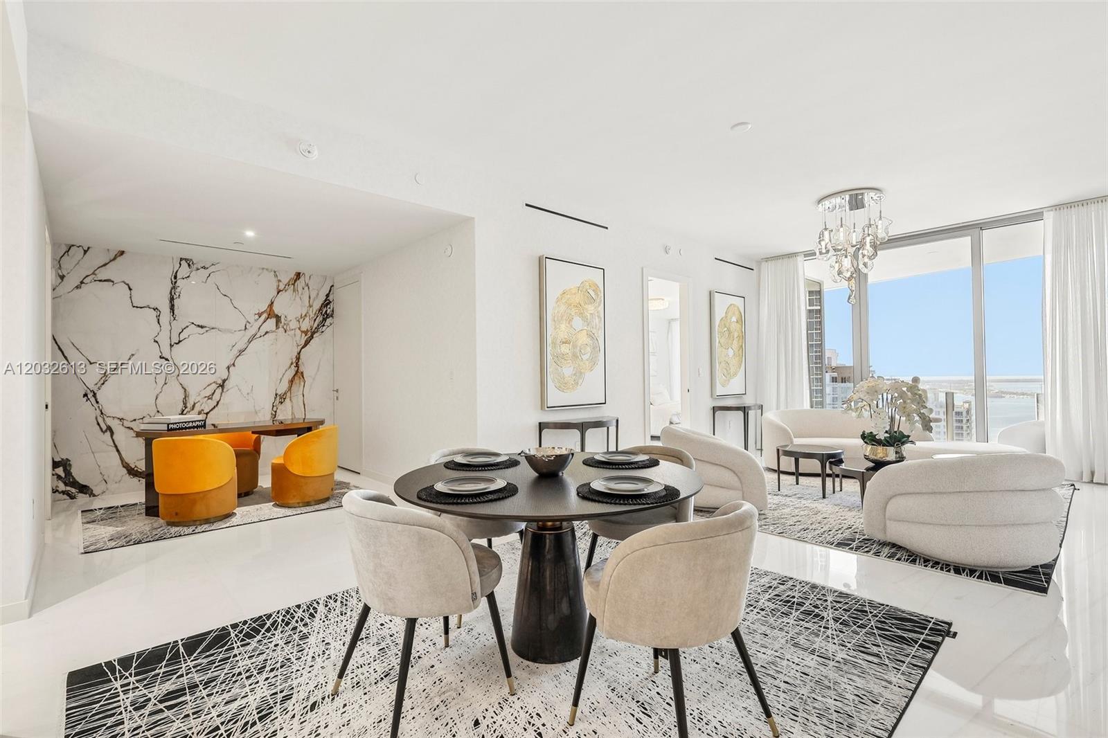 A modern open-concept living and dining area features marble walls, contemporary furniture, and floor-to-ceiling windows — 300 Biscayne Boulevard Way # 3305W, Miami FL 33131, MIAMI, FL