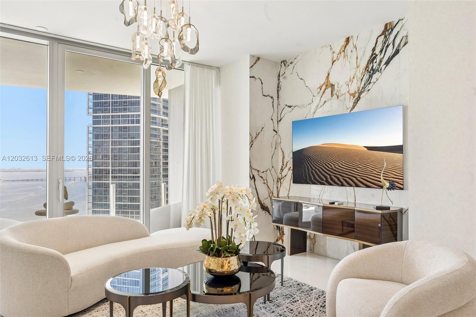 A modern living room features a marble accent wall, a television, and floor-to-ceiling windows — 300 Biscayne Boulevard Way # 3305W, Miami FL 33131, MIAMI, FL