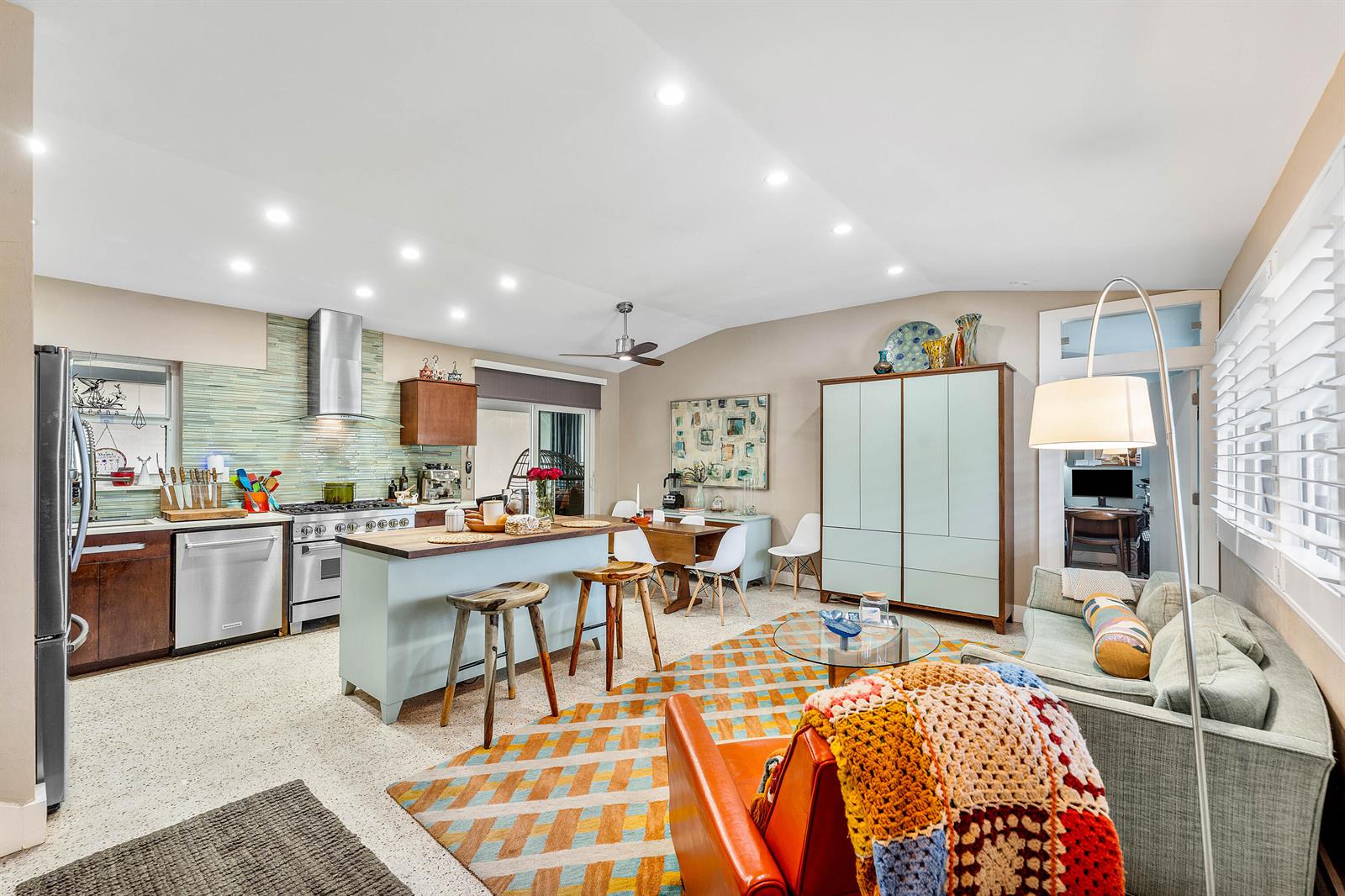 An open-concept kitchen and living area features a central island, colorful rug, and light-colored cabinetry — 1455 NE 4th Avenue, Boca Raton FL 33432, BOCA RATON, FL