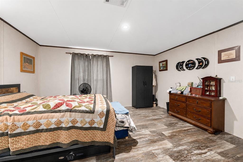 A bathroom with a vanity, open closet, and shelving unit leads into a bedroom — 23707 NE STATE ROAD 26, MELROSE, FL