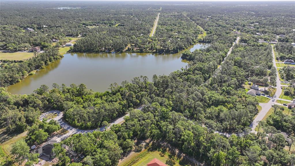 An aerial view of a lake surrounded by dense trees and nearby residential streets — LONGWELL LANE, NORTH PORT, FL