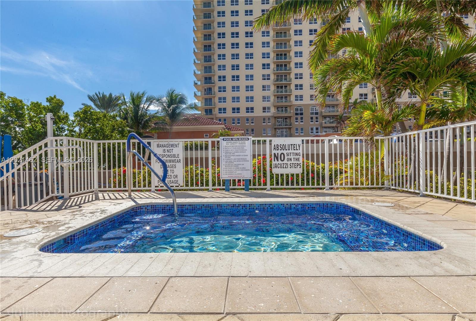 A square tiled hot tub sits on a patio enclosed by a white metal fence — 2030 S Ocean Dr # 908, Hallandale Beach FL 33009, HALLANDALE BEACH, FL