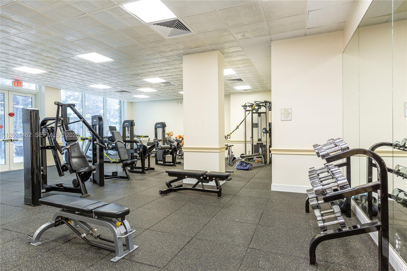 This gym features various weight machines, a dumbbell rack, and a mirrored wall — 2030 S Ocean Dr # 908, Hallandale Beach FL 33009, HALLANDALE BEACH, FL