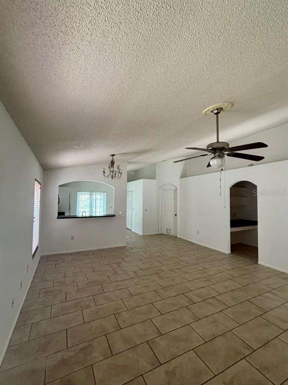 A living room with tile flooring, a ceiling fan, and an arched kitchen pass-through window — 2713 PALM ISLE WAY, ORLANDO, FL