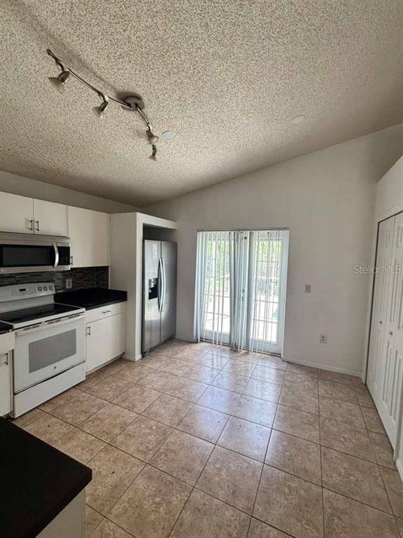 A kitchen with white cabinets, stainless steel appliances, tile flooring, and sliding glass doors — 2713 PALM ISLE WAY, ORLANDO, FL