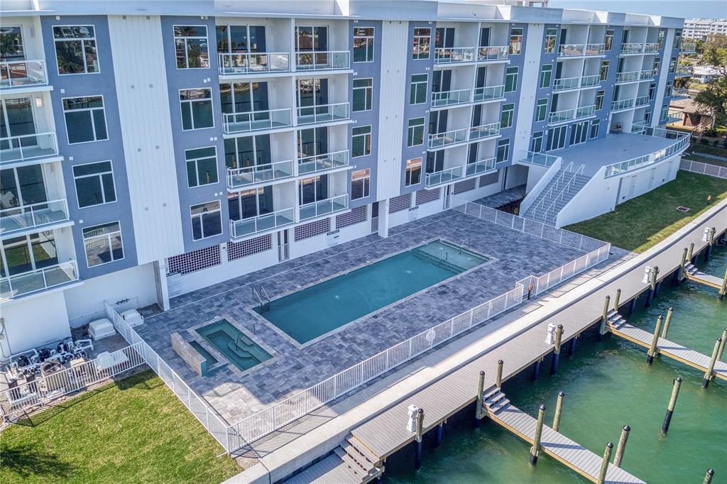 An aerial view of a multi-story apartment building with a pool, hot tub, and dock — 415 ISLAND WAY UNIT 207, CLEARWATER BEACH, FL