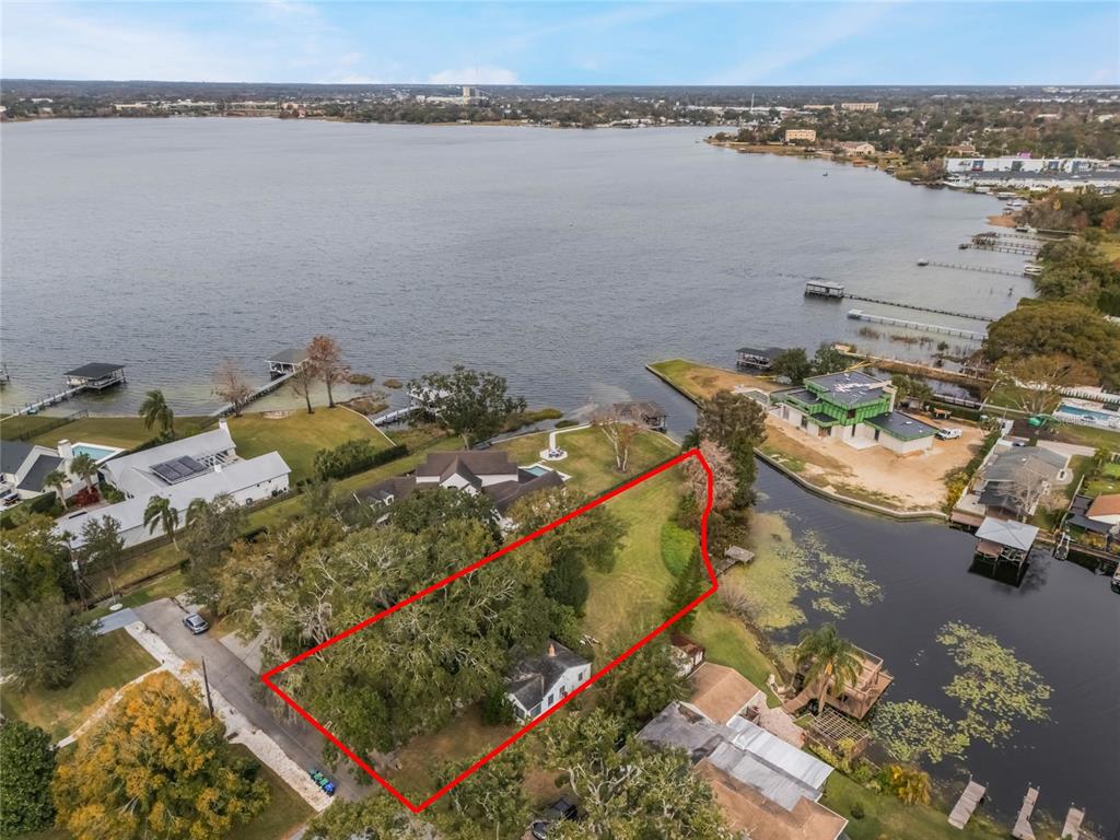 An aerial view shows a house on a large, tree-filled lot bordering a lake — 1113 VENETIAN AVENUE, ORLANDO, FL