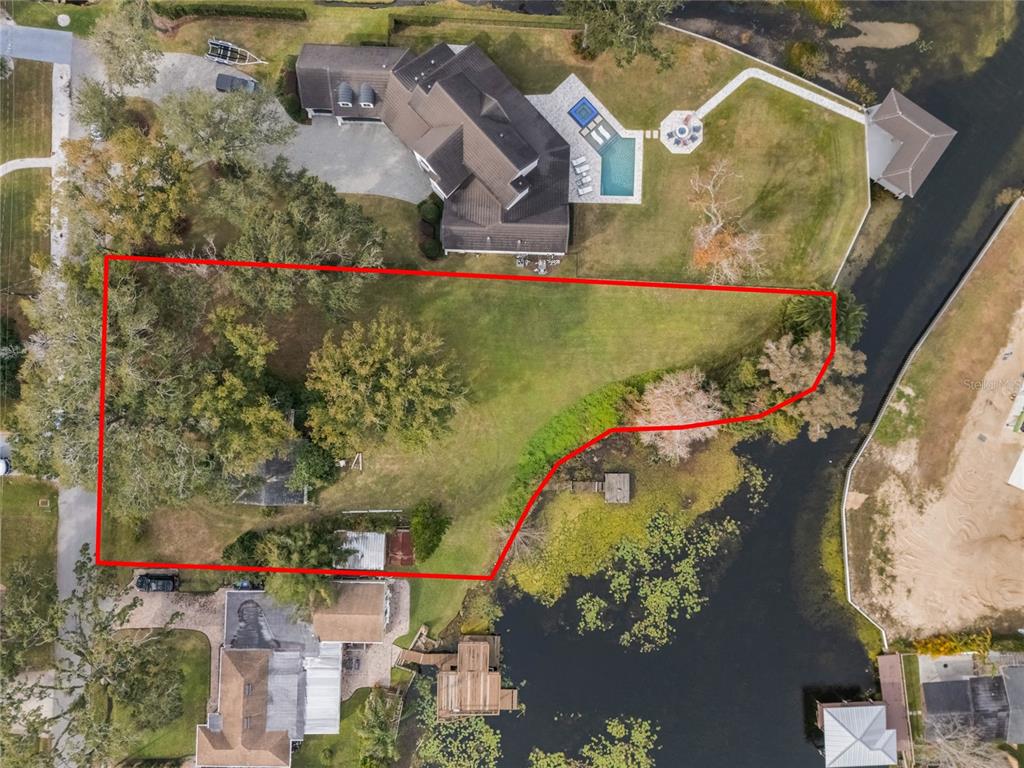 An aerial view shows a large, grassy residential lot outlined in red next to a lake — 1113 VENETIAN AVENUE, ORLANDO, FL