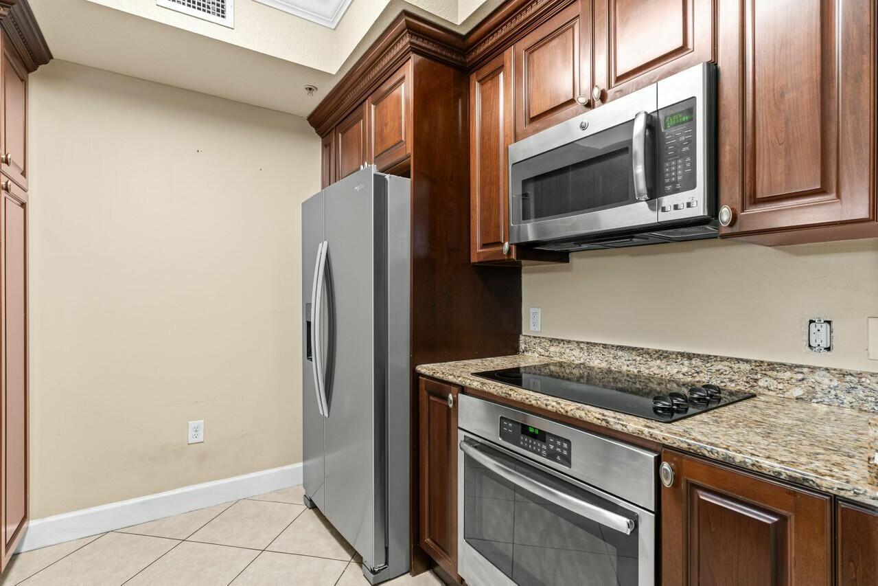 A kitchen features dark wood cabinets, stainless steel appliances, and granite countertops — 1690 Renaissance Commons Boulevard # 1125, Boynton Beach FL 33426, BOYNTON BEACH, FL