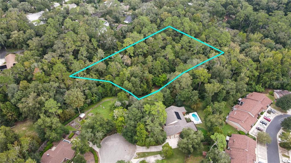 An aerial view shows a wooded lot outlined in blue next to a residential neighborhood — 3960 NW 30TH PLACE, GAINESVILLE, FL