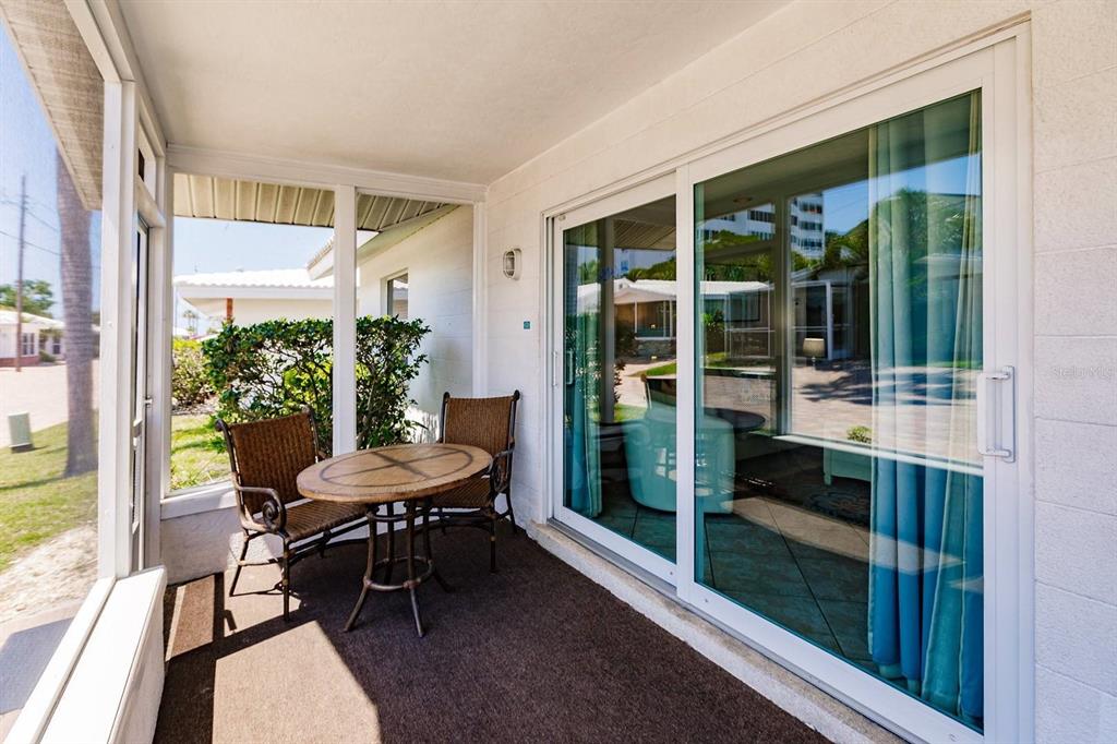 A covered patio features a small table with two chairs and large sliding glass doors — 6020 MIDNIGHT PASS ROAD UNIT 61, SARASOTA, FL