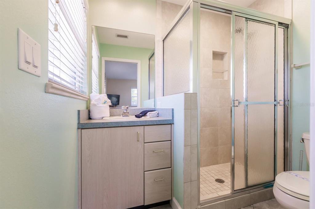 A bathroom features a vanity with a blue countertop, a glass-enclosed shower, and a toilet — 6020 MIDNIGHT PASS ROAD UNIT 61, SARASOTA, FL