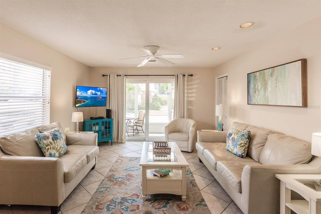 A living room features two beige sofas, a central coffee table, and sliding glass doors — 6020 MIDNIGHT PASS ROAD UNIT 61, SARASOTA, FL