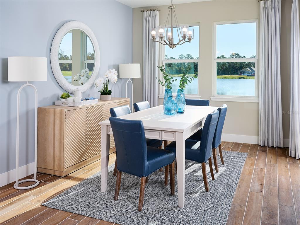 A dining room features a white table with blue chairs, a sideboard, and large windows — 1004 BRITISH CIRCLE, DAYTONA BEACH, FL