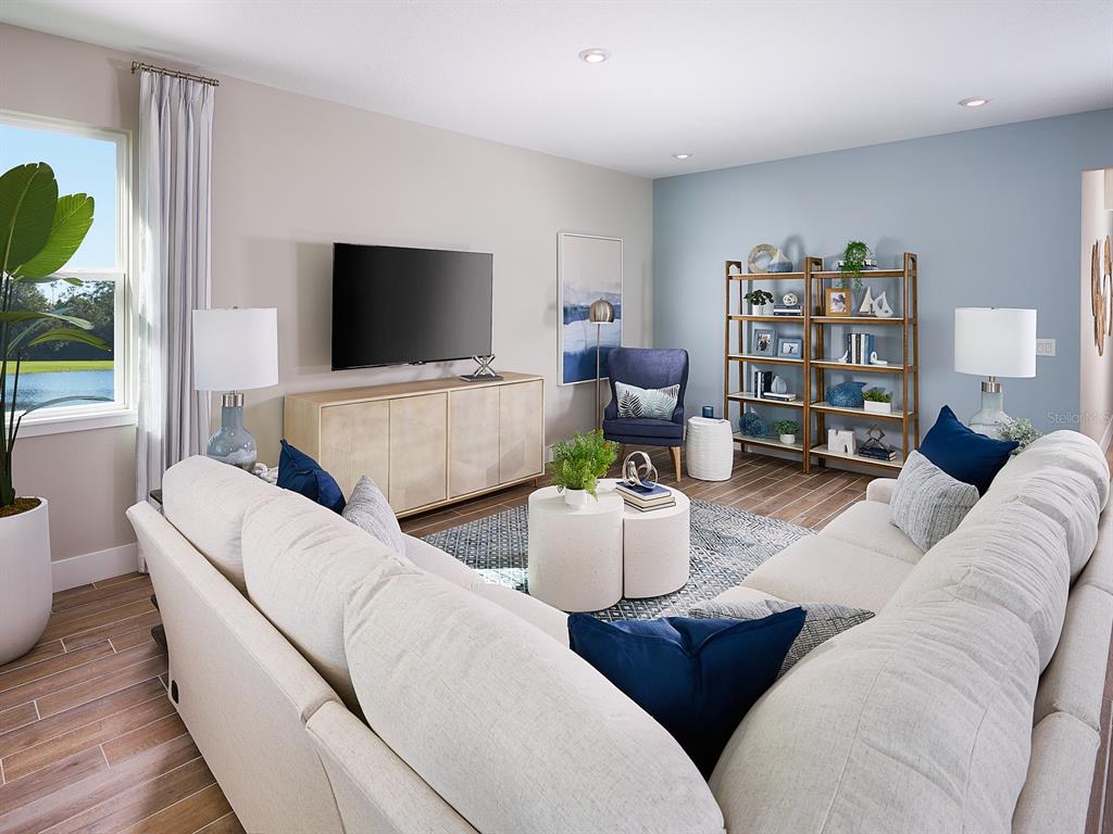 A living room features a large sectional sofa, a television, and a wooden bookshelf — 1004 BRITISH CIRCLE, DAYTONA BEACH, FL
