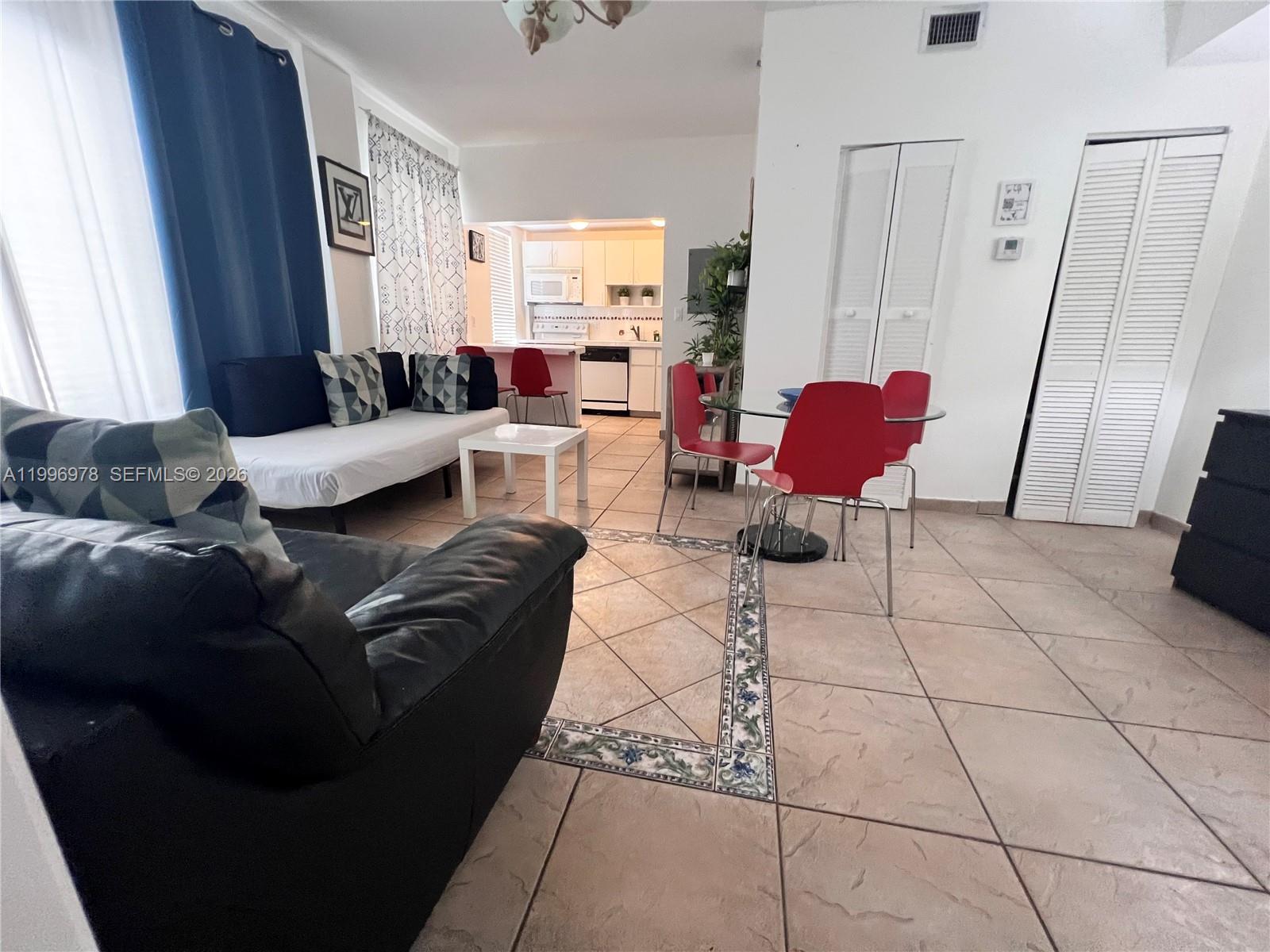 This living and dining area features tile flooring, a white sofa, and red chairs — 918 Ocean Dr # 302, Miami Beach FL 33139, MIAMI BEACH, FL