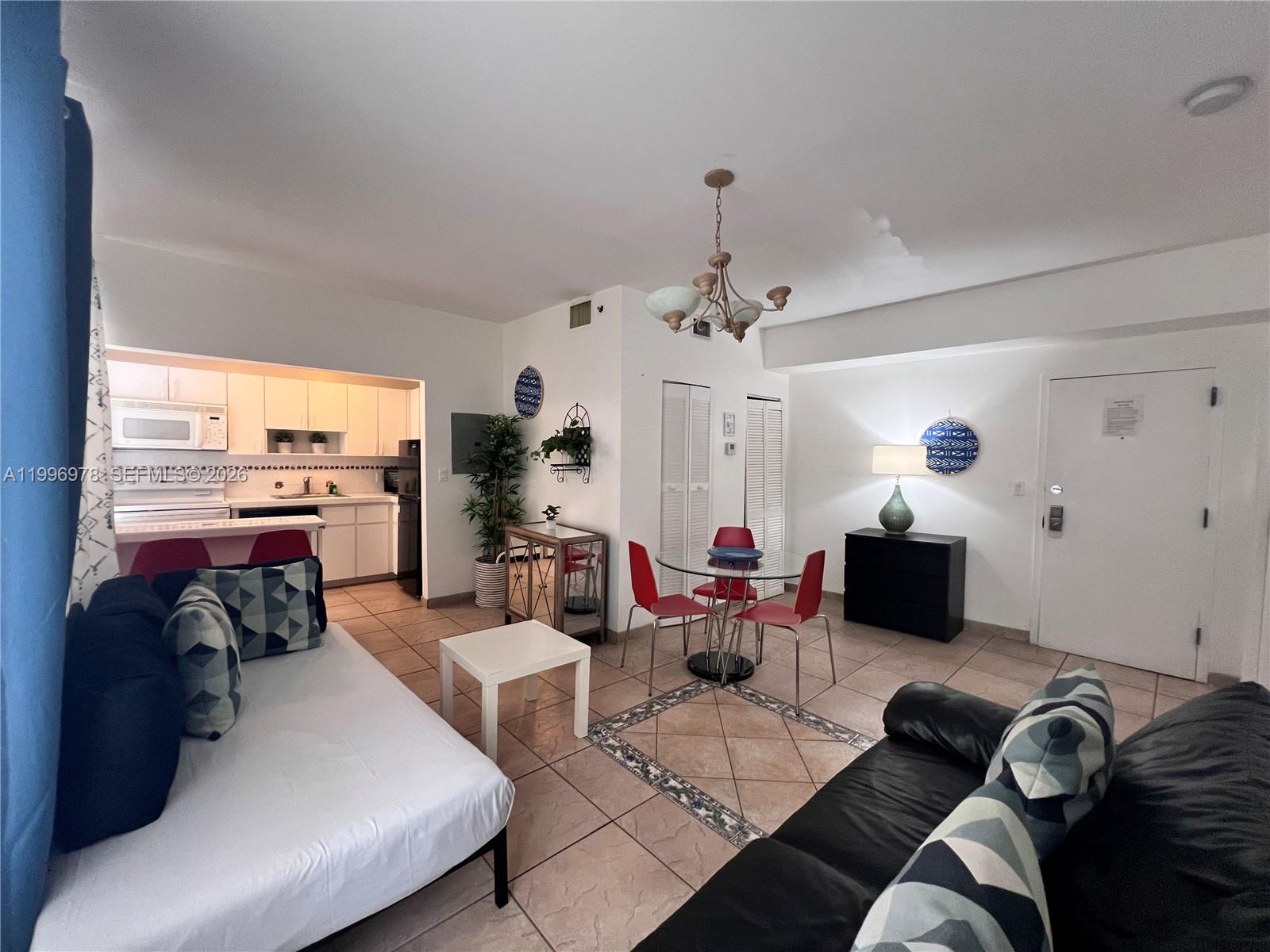 A living room with tile floors, a dining set, and an open kitchen — 918 Ocean Dr # 302, Miami Beach FL 33139, MIAMI BEACH, FL