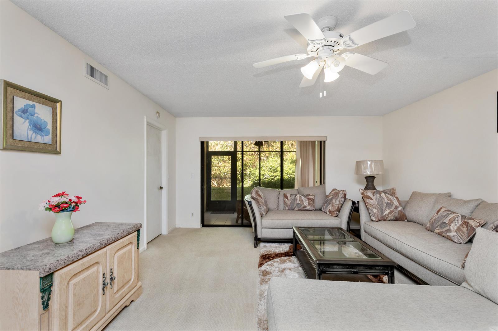 A living room features light-colored furniture, a ceiling fan, and a sliding glass door — 9711 Pavarotti Terrace # 101, Boynton Beach FL 33437, BOYNTON BEACH, FL